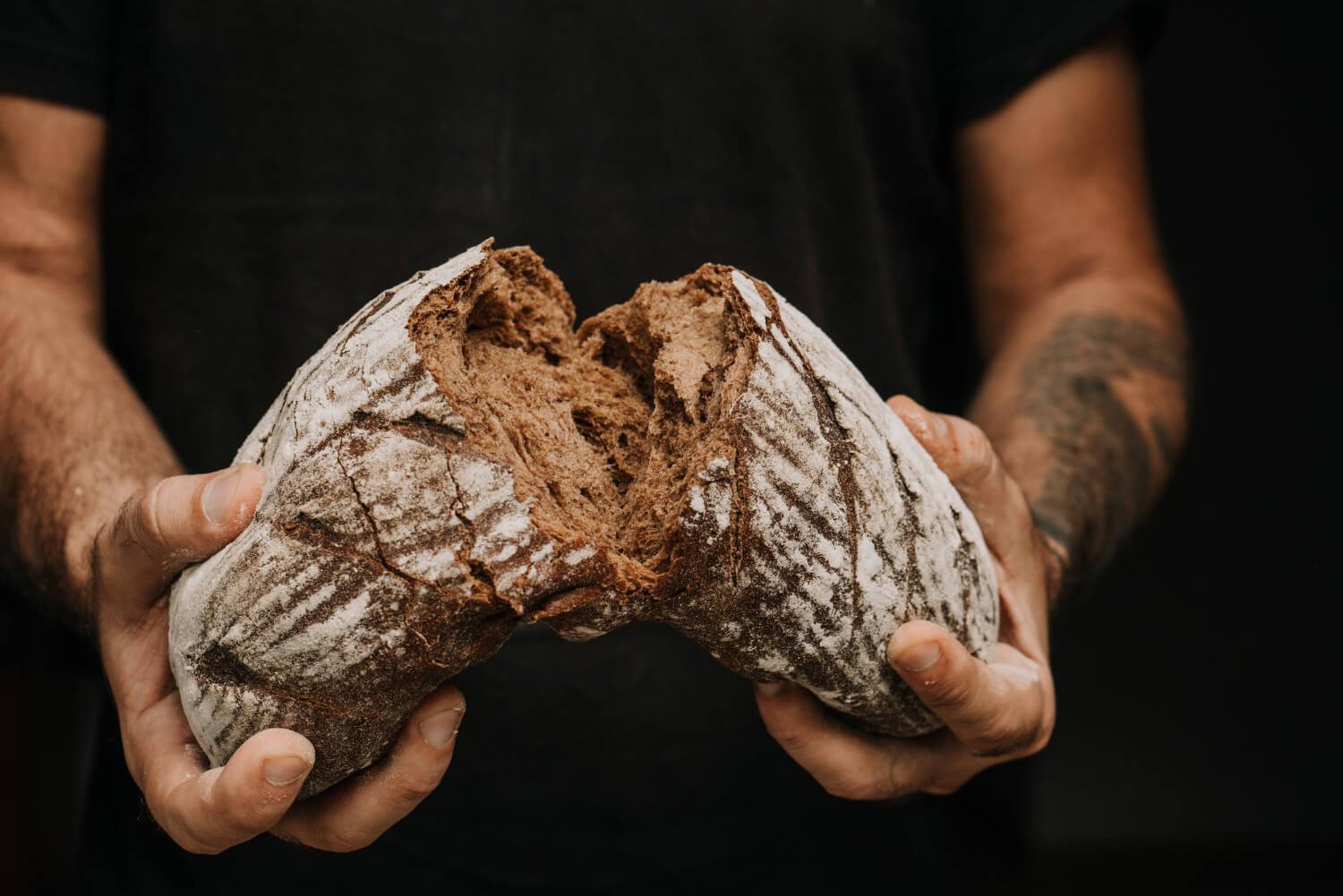 male hands breaking freshly baked bread closeup